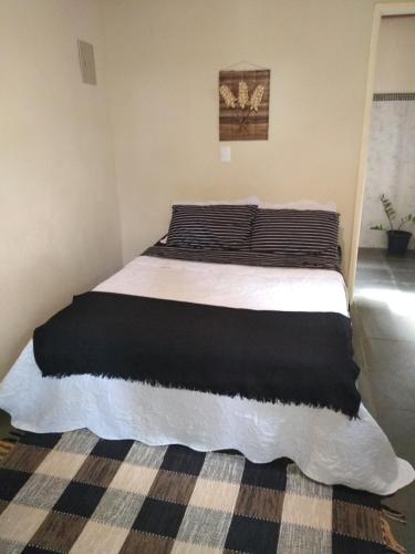 a bed with black and white sheets in a bedroom at Sítio Colibri - Serra da Mantiqueira in Brazópolis