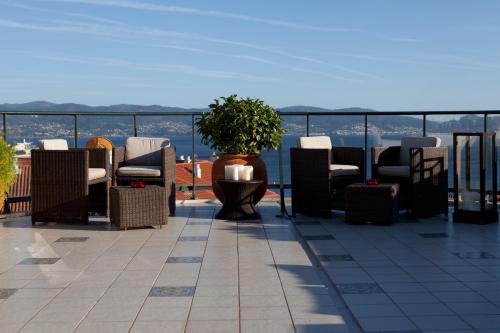 a patio with chairs and a potted plant on a roof at Hotel Carlos I Silgar in Sanxenxo