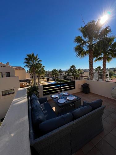 a couch and a table on a balcony with palm trees at Magnifique appartement dans Roda Golf (phase 4) in San Javier