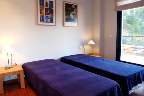 two beds in a hotel room with blue sheets at VISTA MAR - MEGIN in Tamariu
