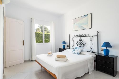 a bedroom with a large white bed with blue lamps at Villa Moll Moll in Cala Blanca