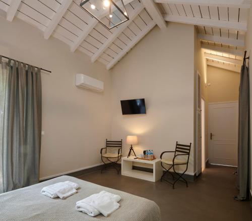 a bedroom with a bed and two chairs and a tv at Varaba Country House in Markopoulo