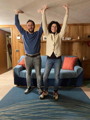 a man and woman standing in a living room with their arms in the air at Jack's Nest in Campertogno