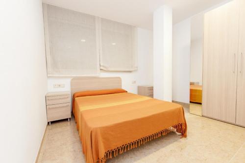 a bedroom with a bed with an orange blanket on it at Ermitana 6 in Peñíscola