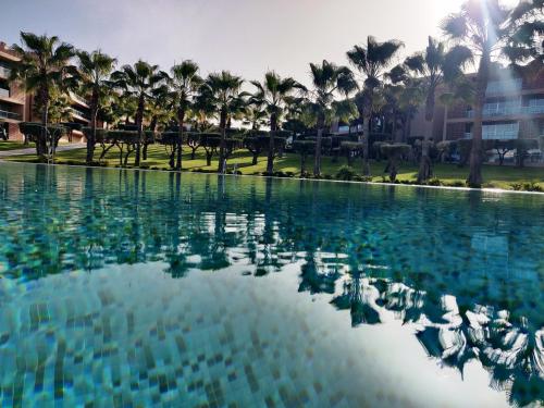 a pool of water with palm trees in the background at Charming apartment Herdade dos Salgados - Vila das Lagoas T2 in Guia