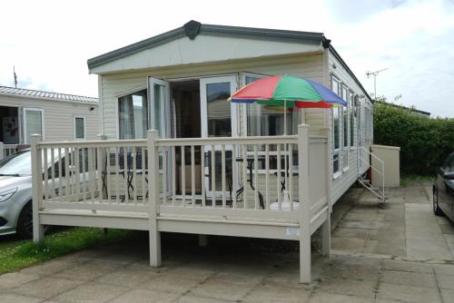 a small house with an umbrella on a porch at Cozy Hunstanton caravan sleeps 8 pets go free in Hunstanton