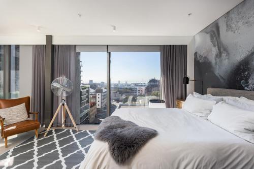 een slaapkamer met een groot bed en een groot raam bij Always-Power Trendy De Waterkant Loft in Kaapstad