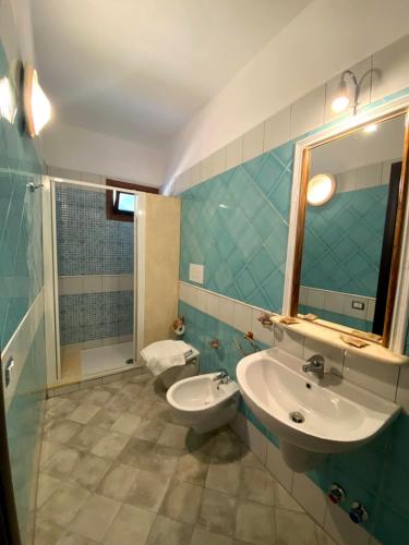 uma casa de banho com um lavatório, um WC e um espelho. em Guest House by Sos Flores em Tortolì