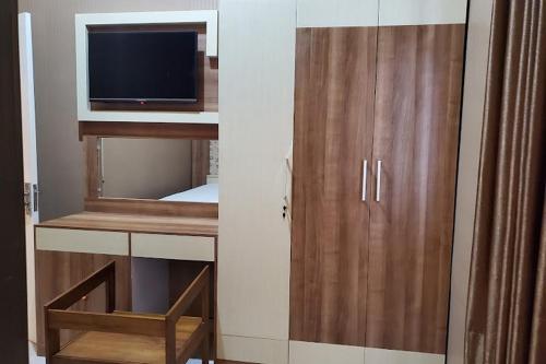 Cette chambre comprend une armoire avec une télévision et une chaise. dans l'établissement RedDoorz near Simpang Tujuh Kudus, à Kudus