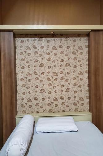 Bett mit einem Kopfteil mit einer Wand mit einem Muster in der Unterkunft RedDoorz near Simpang Tujuh Kudus in Kudus