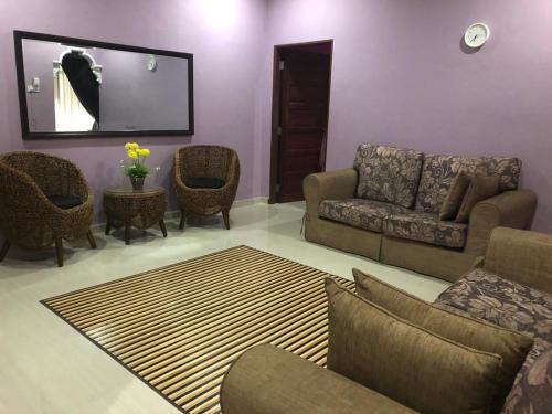 a living room with a couch and chairs and a mirror at afza homestay Bonda Bukit Besi in Kampong Kuala Talam