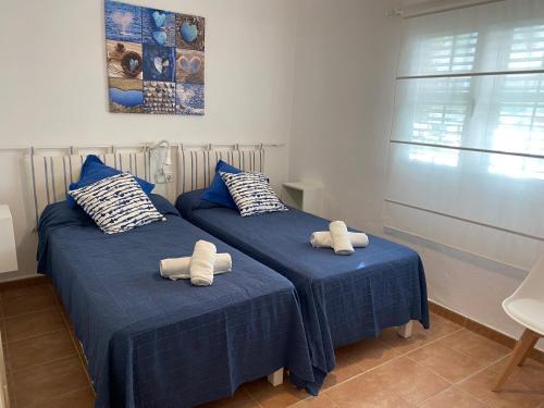 two twin beds in a room with blue sheets at MARINE APARTMENT in Es Pujols