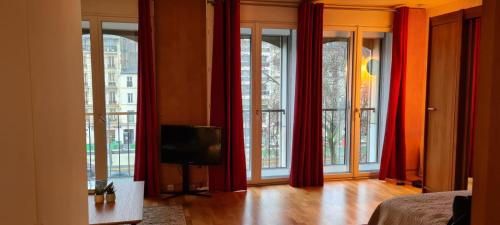 - un salon avec des rideaux rouges et une télévision dans l'établissement Neuilly Paradise, à Neuilly-sur-Seine