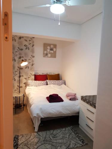 1 dormitorio con 1 cama con sábanas blancas y almohadas rojas en EL MAR TE ESPERA, en Grao de Castellón