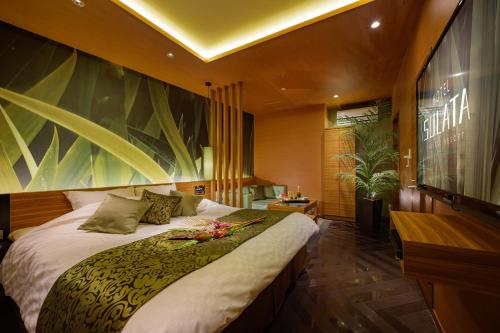 a bedroom with a bed and a large painting on the wall at Hotel Sulata Yamagata Airport in Higashine