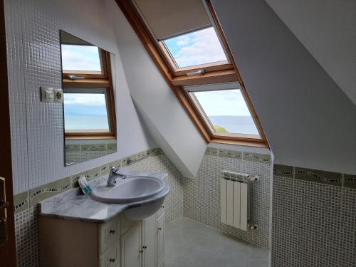 a bathroom with a sink and two windows at Dúplex 4 dormitorios en Playa Rapadoira in Foz