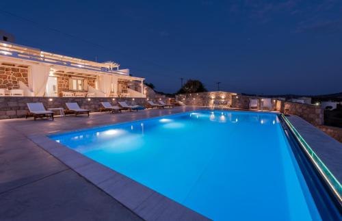 a swimming pool at night with a building in the background at Anemi Suites in Adamas