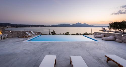 a villa with a swimming pool and a view of the water at Anemi Suites in Adamas
