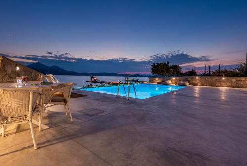 a patio with a table and a swimming pool at night at Anemi Suites in Adamas