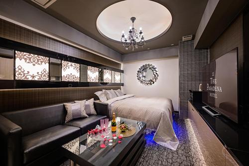 a bedroom with a bed and a couch and a chandelier at HOTEL パサディナ11 Adult Only in Saitama