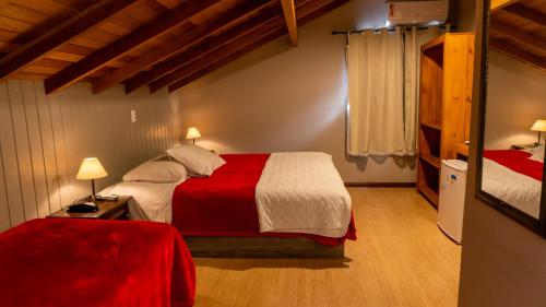 um quarto com uma cama grande e um cobertor vermelho em Aardvark Inn Pousada em Gramado