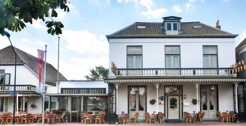 een wit gebouw met tafels en stoelen ervoor bij Hotel Bakker in Vorden