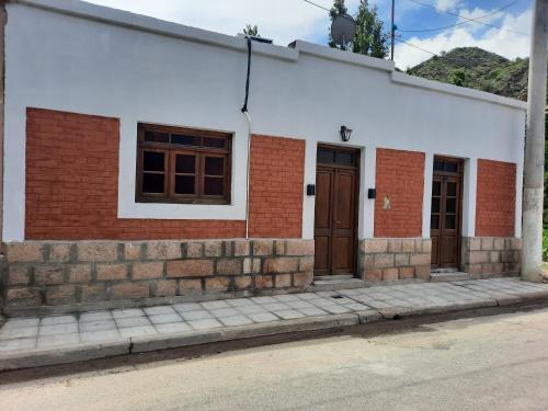 biały budynek z brązowymi drzwiami na ulicy w obiekcie Casa De Antaño w mieście Belén