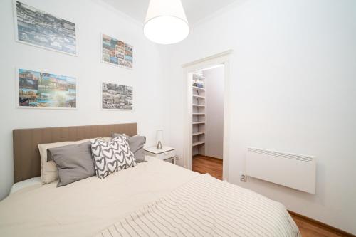a white bedroom with a bed and some pictures on the wall at Cozy apartment in Budapest near Gellért Hill in Budapest