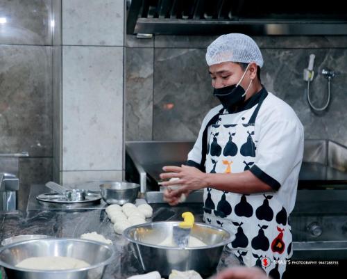 a man in a kitchen preparing food in a kitchen at Hotel Crystals Cove in Thekkady