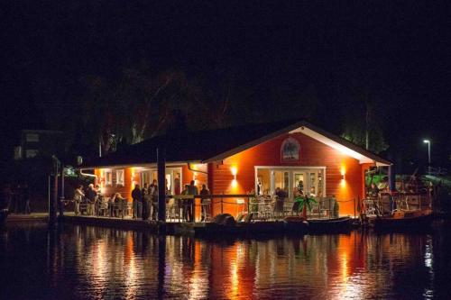 a restaurant on a dock on a river at night at Hausboot La Mare Emma in Weyhe