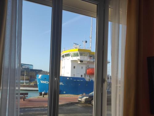 a view of a cruise ship through a window at LE WELCOME vue port appartement plain pied in Fécamp