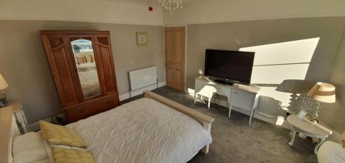 a bedroom with a bed and a flat screen tv at Rocky Cove Bed and Breakfast in Ilfracombe