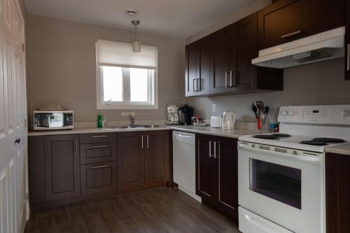 a kitchen with wooden cabinets and white appliances at The Killick Inn & Suites in Arnold's Cove