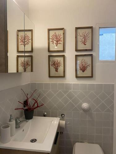 La salle de bains est pourvue d'un lavabo et de 4 photos sur le mur. dans l'établissement Casa vacanza al Duomo: Cefalù, à Cefalù