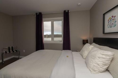 a bedroom with a large white bed with a window at The Killick Inn & Suites in Arnold's Cove