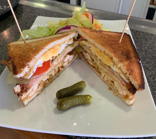 a sandwich and a pickle on a white plate at Mariana Plage in La Marana