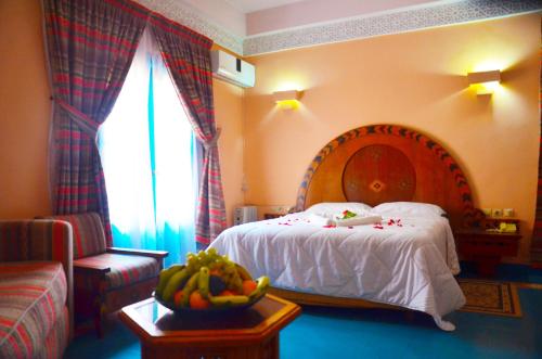 a bedroom with a bed and a table with a bowl of fruit at Hôtel Auberge du Littoral in Aourir