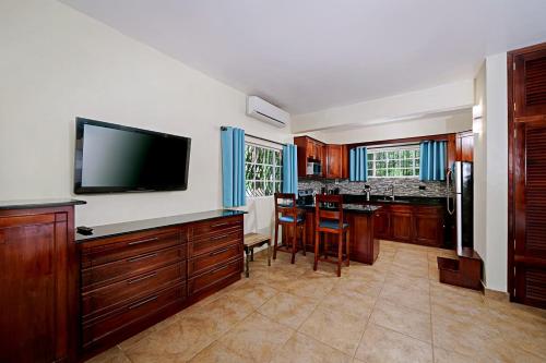 a kitchen with wooden cabinets and a flat screen tv at Beach House Condos, Negril in Negril