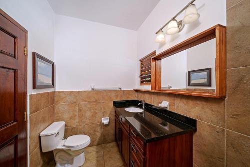 a bathroom with a toilet and a sink and a mirror at Beach House Condos, Negril in Negril
