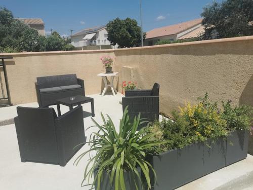 un patio con 2 sillas, una mesa y plantas en Appartement agréable et spacieux ensoleillé, en Valros