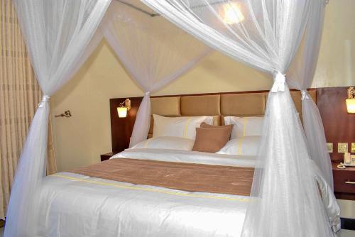 une chambre avec un lit à baldaquin avec des rideaux blancs dans l'établissement Studio - Sleeps 2 - Free Shuttle, à Entebbe