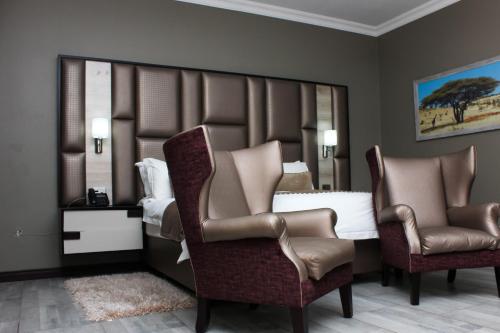 sypialnia z 2 krzesłami i łóżkiem z lustrem w obiekcie Vahlavi Lodge w mieście Giyani