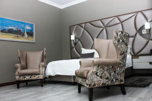 - une chambre avec un grand lit et deux chaises dans l'établissement Vahlavi Lodge, à Giyani
