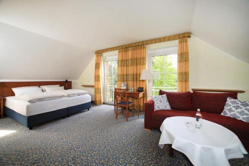 ein Hotelzimmer mit einem Bett und einem Sofa in der Unterkunft Landidyll Hotel Erbgericht Tautewalde in Wilthen