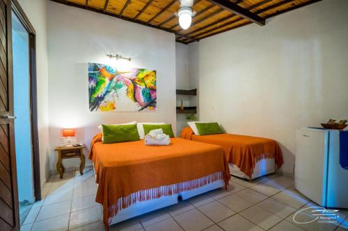 a bedroom with two beds and a painting on the wall at Pousada Oasis in Pipa