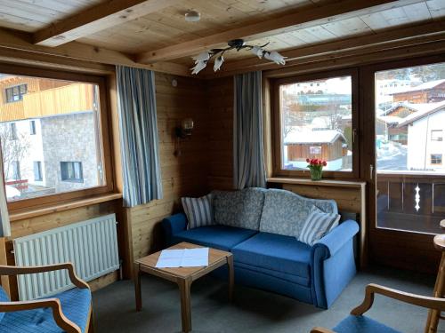 a living room with a blue couch and windows at Appartements Rendl in Sankt Anton am Arlberg