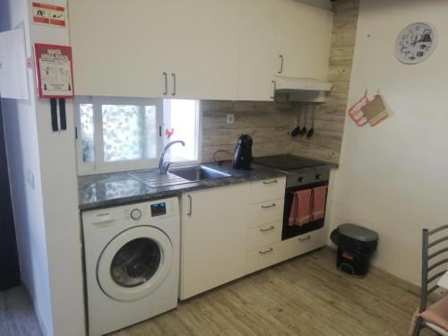 a kitchen with a washing machine and a sink at Casa da Praia Alfarim in Sesimbra