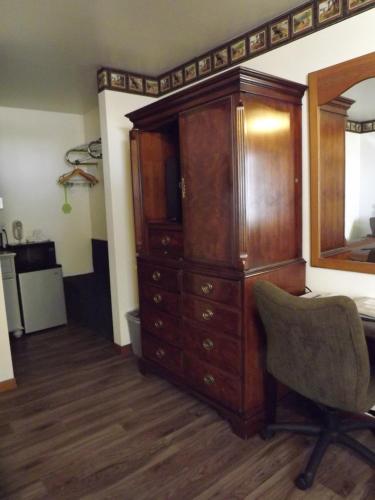 a bedroom with a large wooden cabinet and a chair at Crest Country Inn in Williamsburg