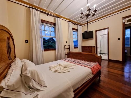 a bedroom with a bed with white sheets and windows at Teatro Hotel Boutique in Ouro Preto