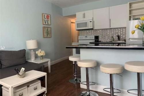 ein Wohnzimmer mit einer Küche und einer Bar mit Hockern in der Unterkunft Sun Sand and Love - Lovely 2 Beds, 2 Bath Condo in Miami Beach